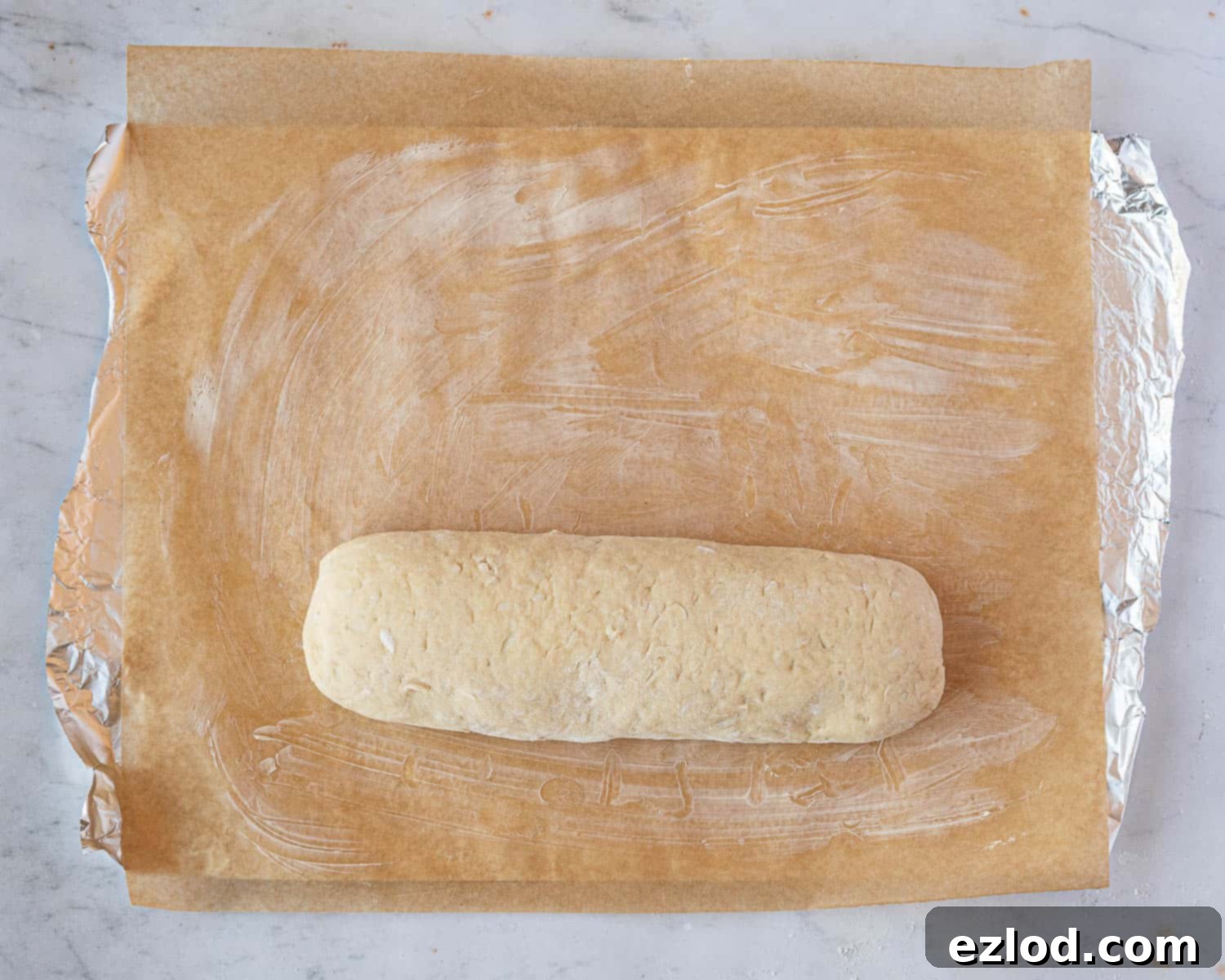 Luscious Vegan Jam Roly-Poly 11 Step 8 in making vegan jam roly-poly: the rolled roly-poly placed seam-side down onto the greased baking parchment.