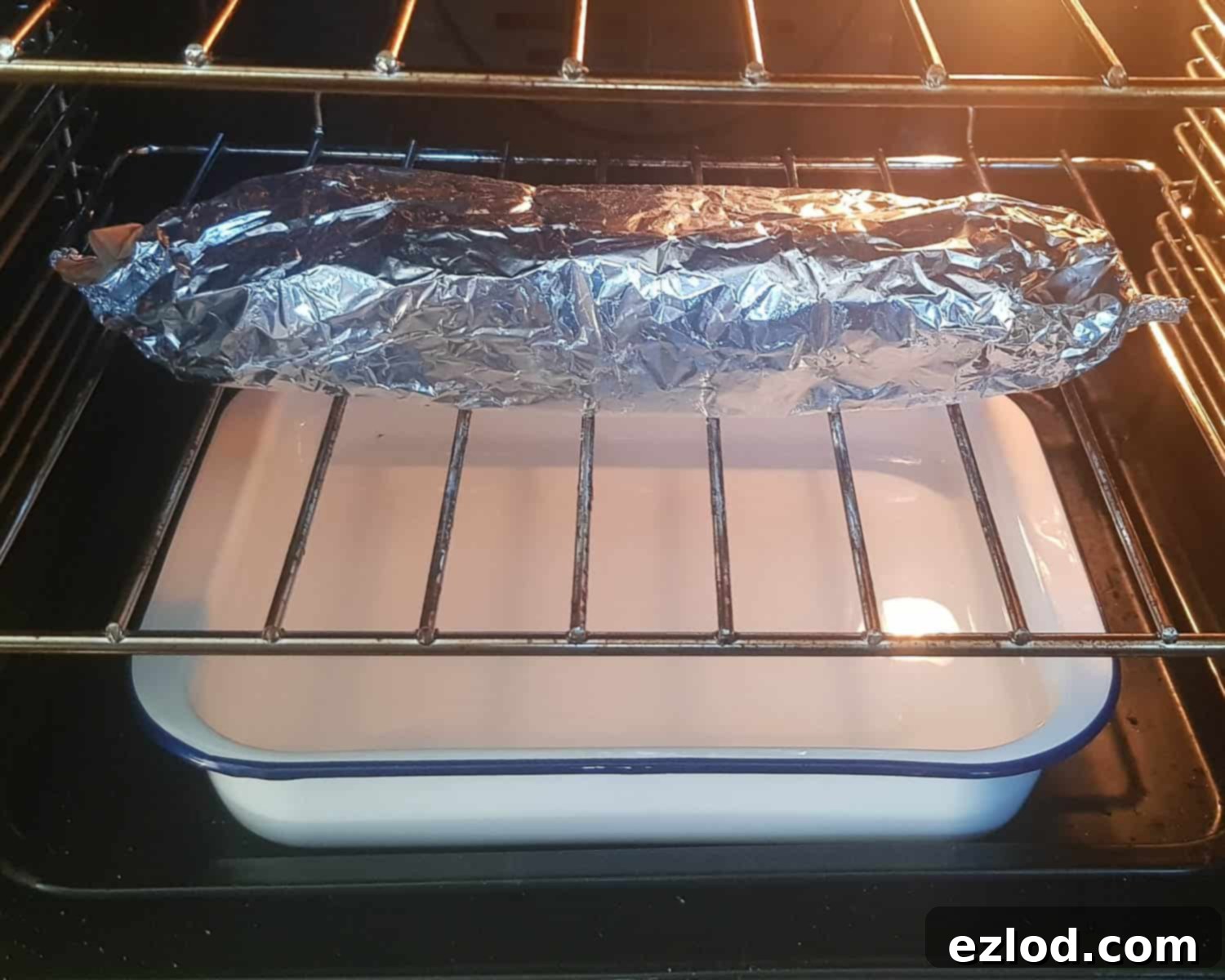 Luscious Vegan Jam Roly-Poly 13 Step 10 in making vegan jam roly-poly: the wrapped roly-poly parcel placed on the oven rack, above a roasting tin filled with boiling water, baking in the oven.