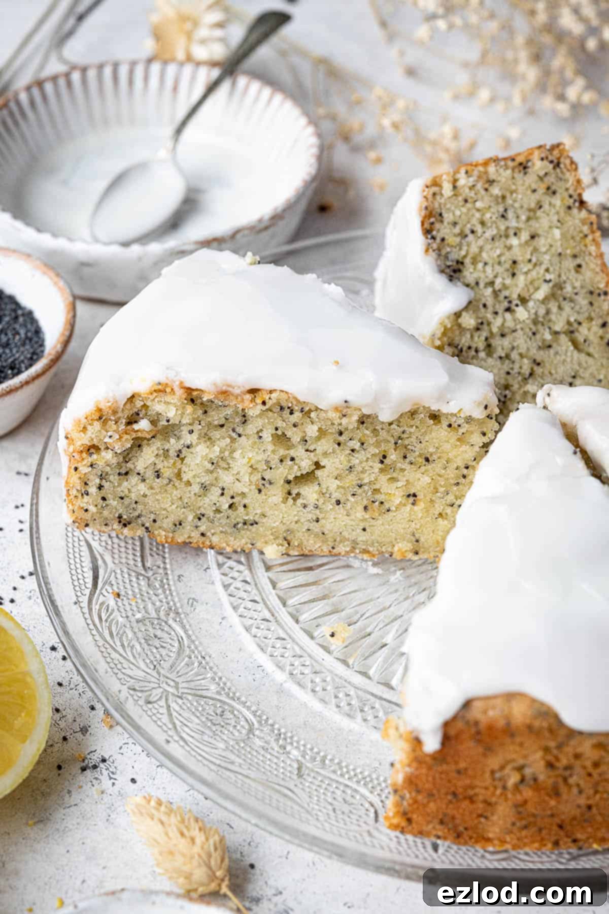 Zesty Vegan Lemon Poppy Seed Cake 11 A close-up view of a large slice of the vegan lemon poppy seed cake, showing its perfectly moist, tender crumb speckled with poppy seeds and a glossy lemon glaze.