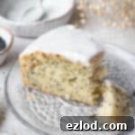 Zesty Vegan Lemon Poppy Seed Cake 12 A slice of vegan lemon poppy seed cake on a glass plate with a forkful removed.