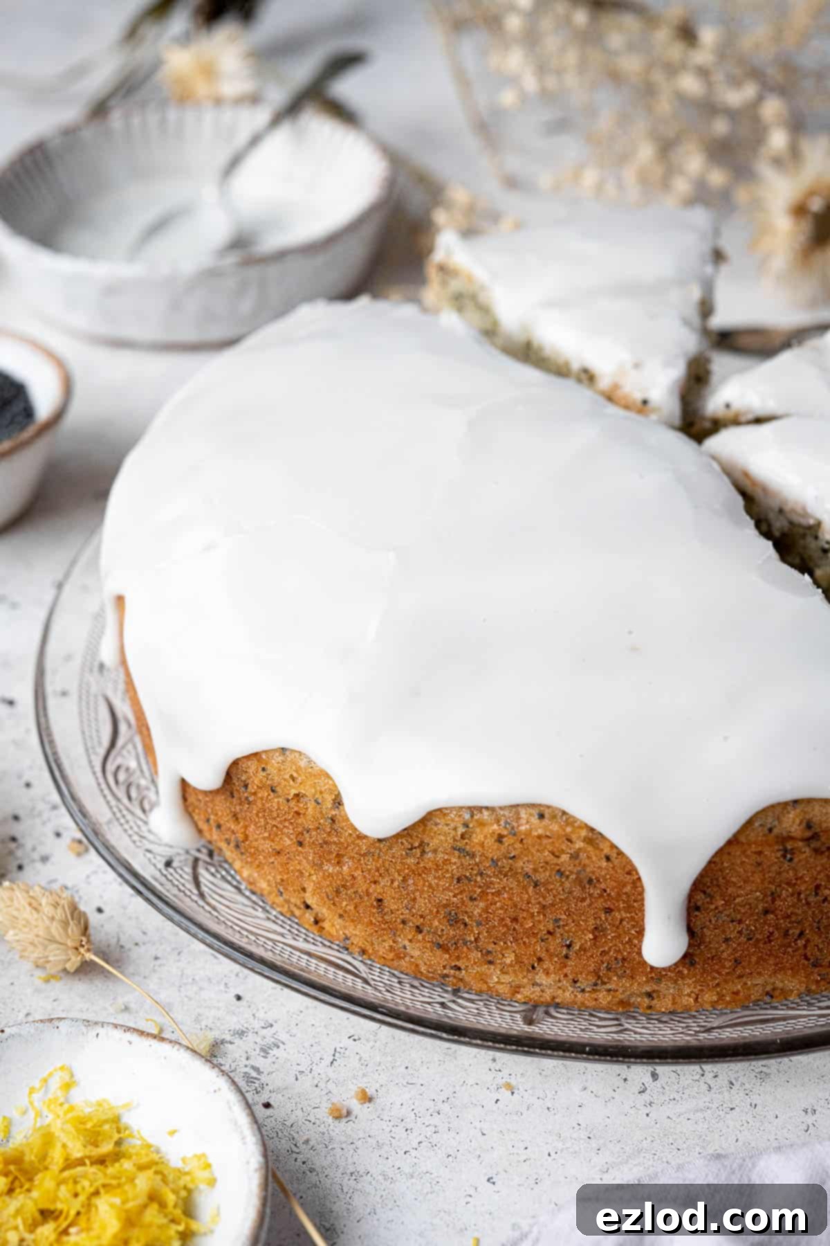 Zesty Vegan Lemon Poppy Seed Cake 4 A close-up shot of the top of the vegan lemon poppy seed cake, showing the smooth, glossy lemon icing drizzled over the golden-brown surface.