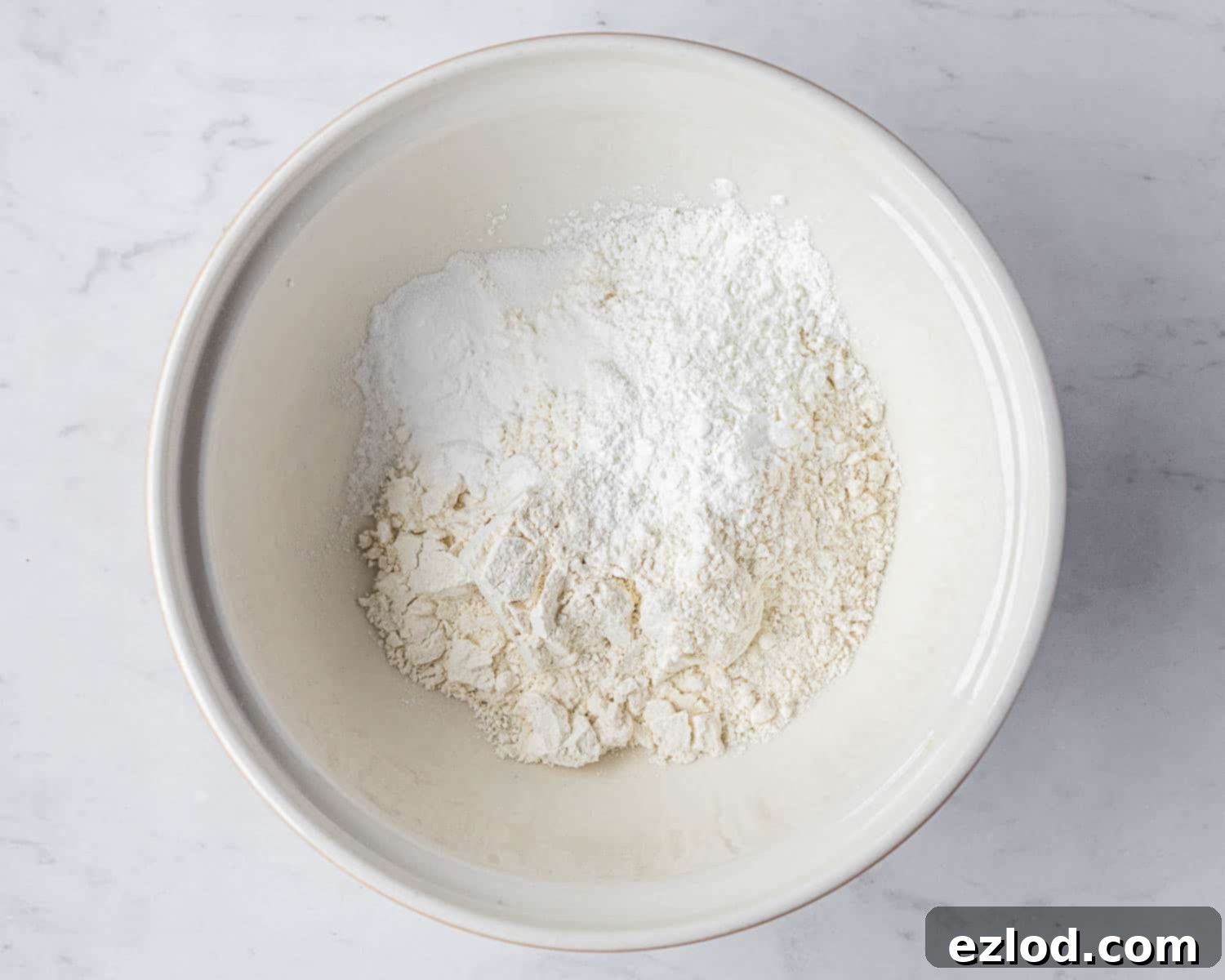 Zesty Vegan Lemon Poppy Seed Cake 5 Step 1: All the dry ingredients – plain flour, cornflour, baking powder, baking soda, and salt – are sifted together in a large mixing bowl.