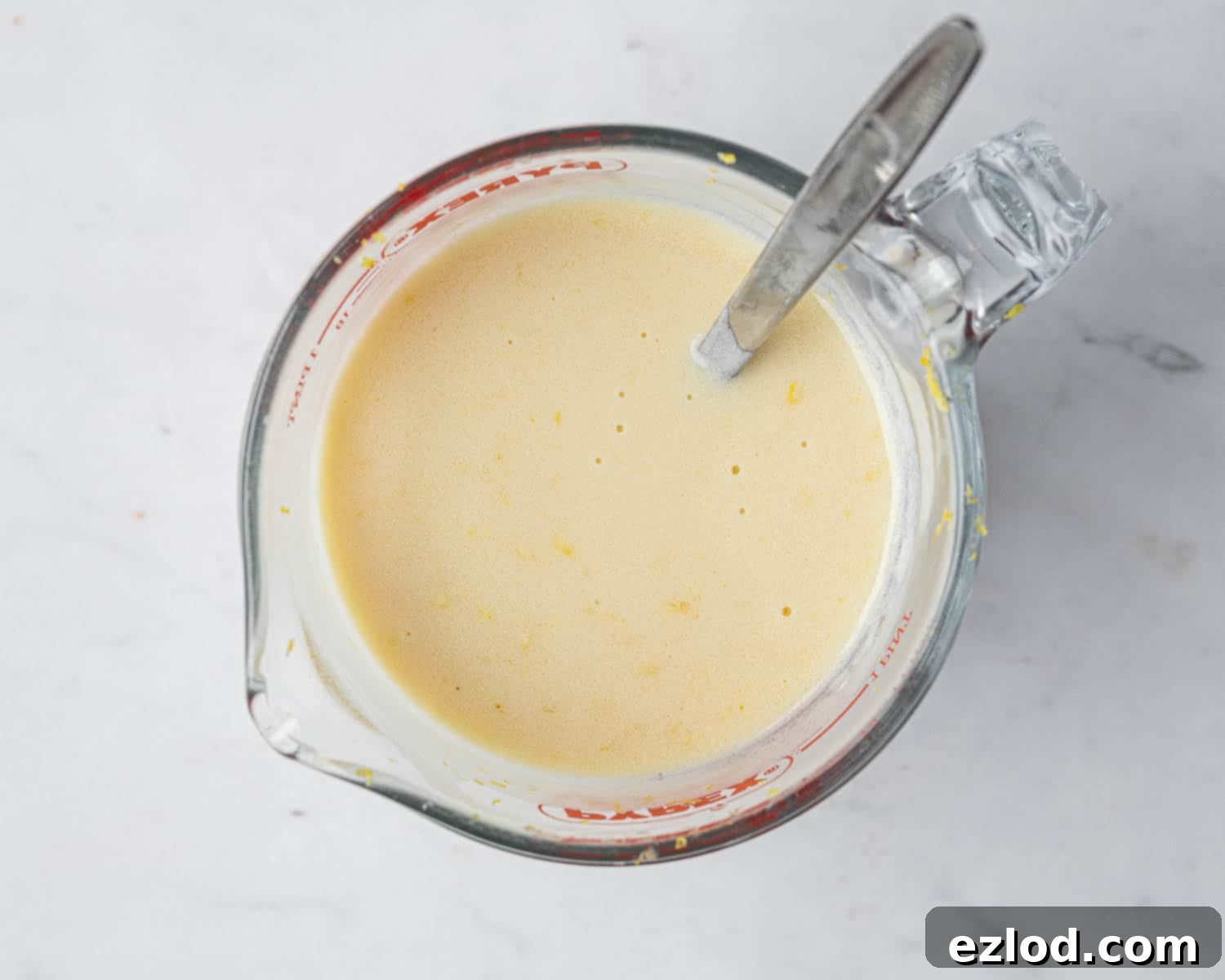 Zesty Vegan Lemon Poppy Seed Cake 6 Step 2: The wet ingredients – lemon zest, lemon juice, melted vegan butter, oil, yogurt, and non-dairy milk – are thoroughly whisked together in a measuring jug.