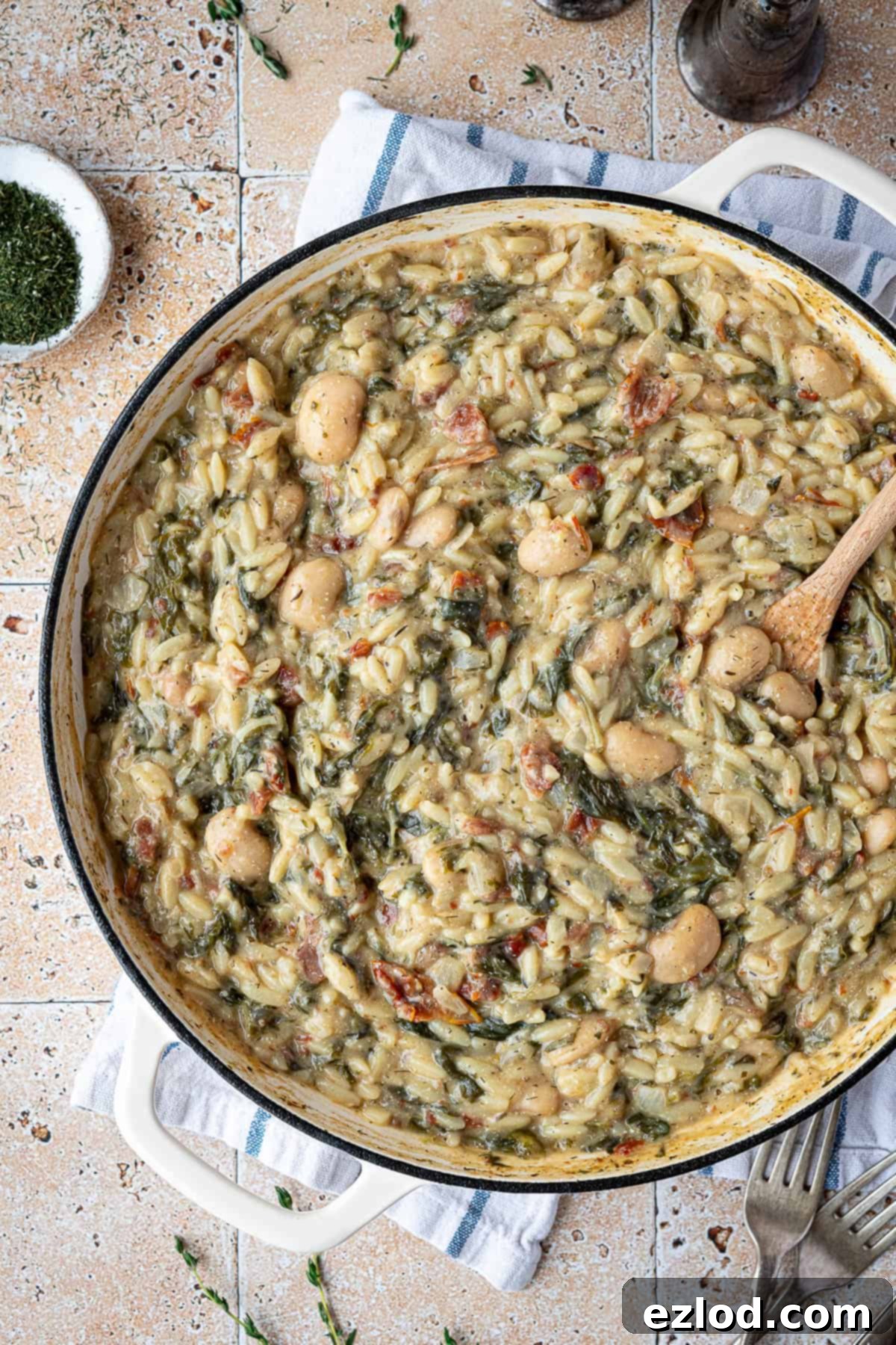 Velvety Vegan Spinach Orzo 8 Close up of a pan of vegan creamy spinach orzo on a tiled surface.