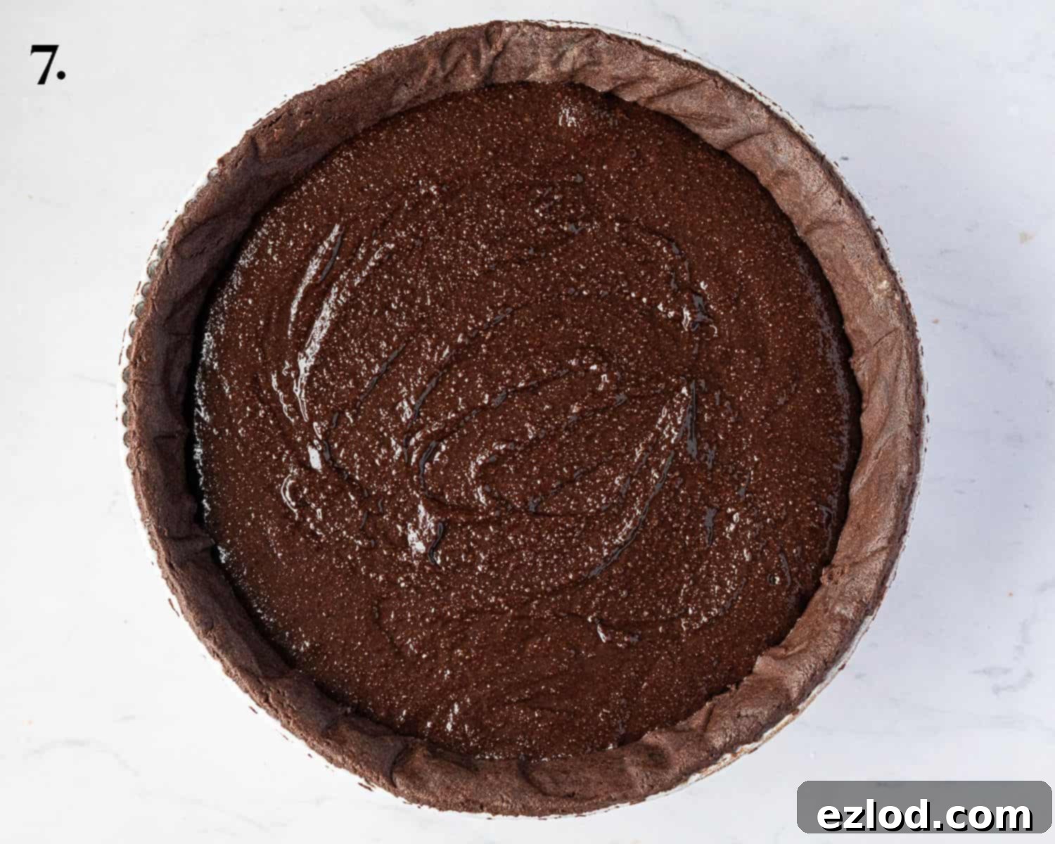 Rich Vegan Chocolate Pear Almond Tart 11 Step-by-step image displaying the chocolate frangipane filling poured evenly into the blind-baked pastry case, ready for pears.