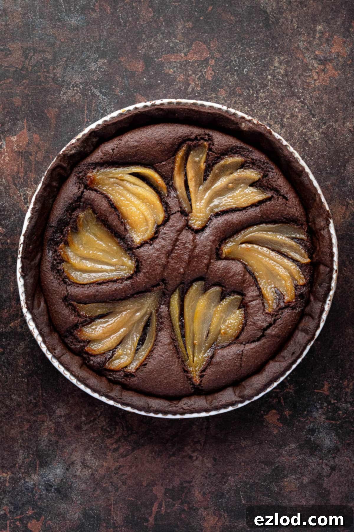 Rich Vegan Chocolate Pear Almond Tart 14 The fully baked vegan chocolate pear frangipane tart, golden and perfectly set, displayed on a dark surface.