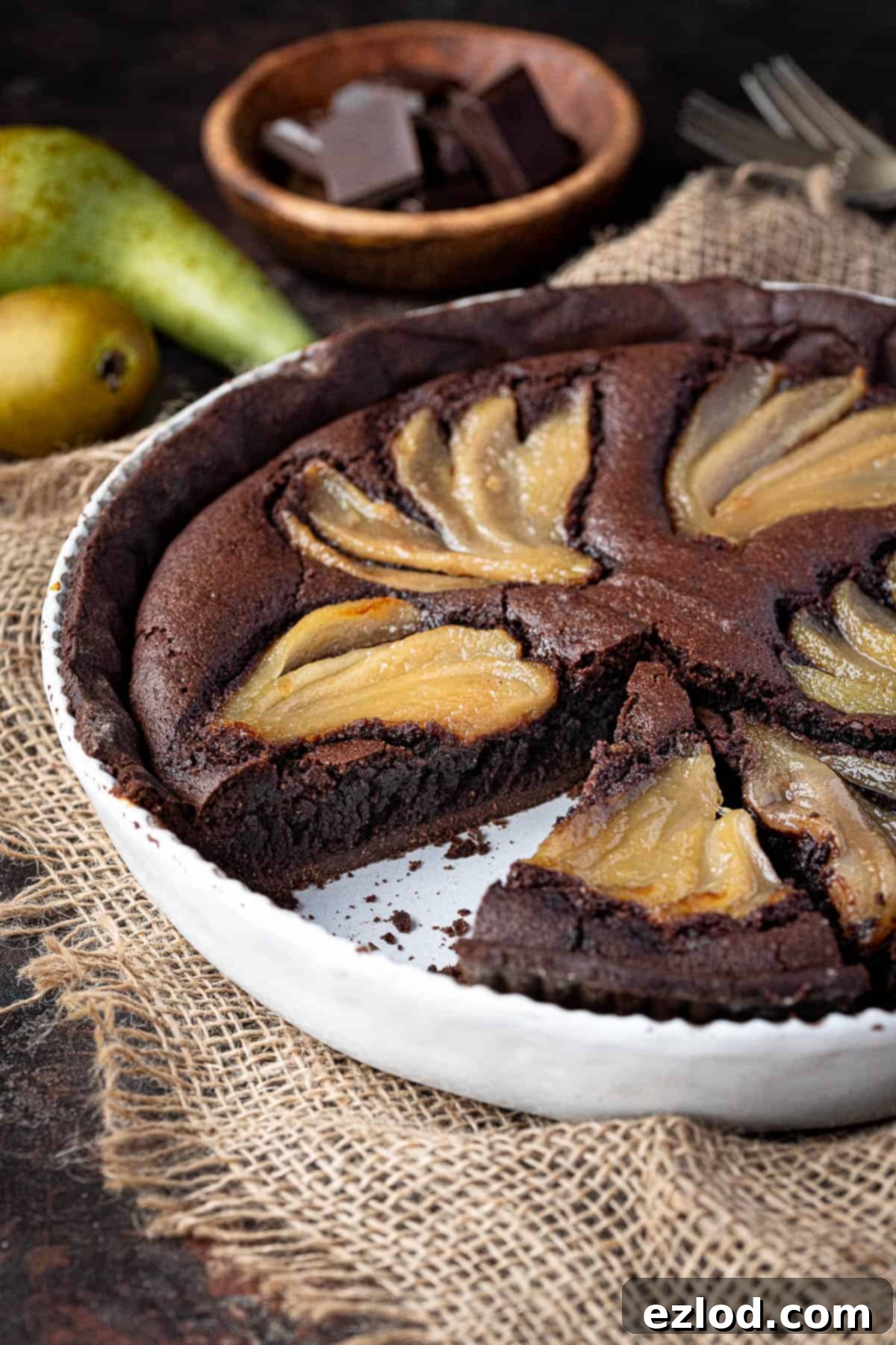 Rich Vegan Chocolate Pear Almond Tart 4 A close-up shot of a perfectly sliced vegan chocolate pear frangipane tart, revealing the layers of crisp pastry, fudgy frangipane, and tender pear.