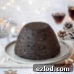Guilt-Free Vegan Chocolate Christmas Pudding 14 Vegan chocolate Christmas pudding on a plate surrounded by Christmas decorations and glasses of rum.
