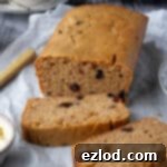 Zesty Vegan Marmalade Tea Loaf 11 Easy vegan marmalade tea loaf on a sheet of baking parchment on a wooden table with a cup of tea.