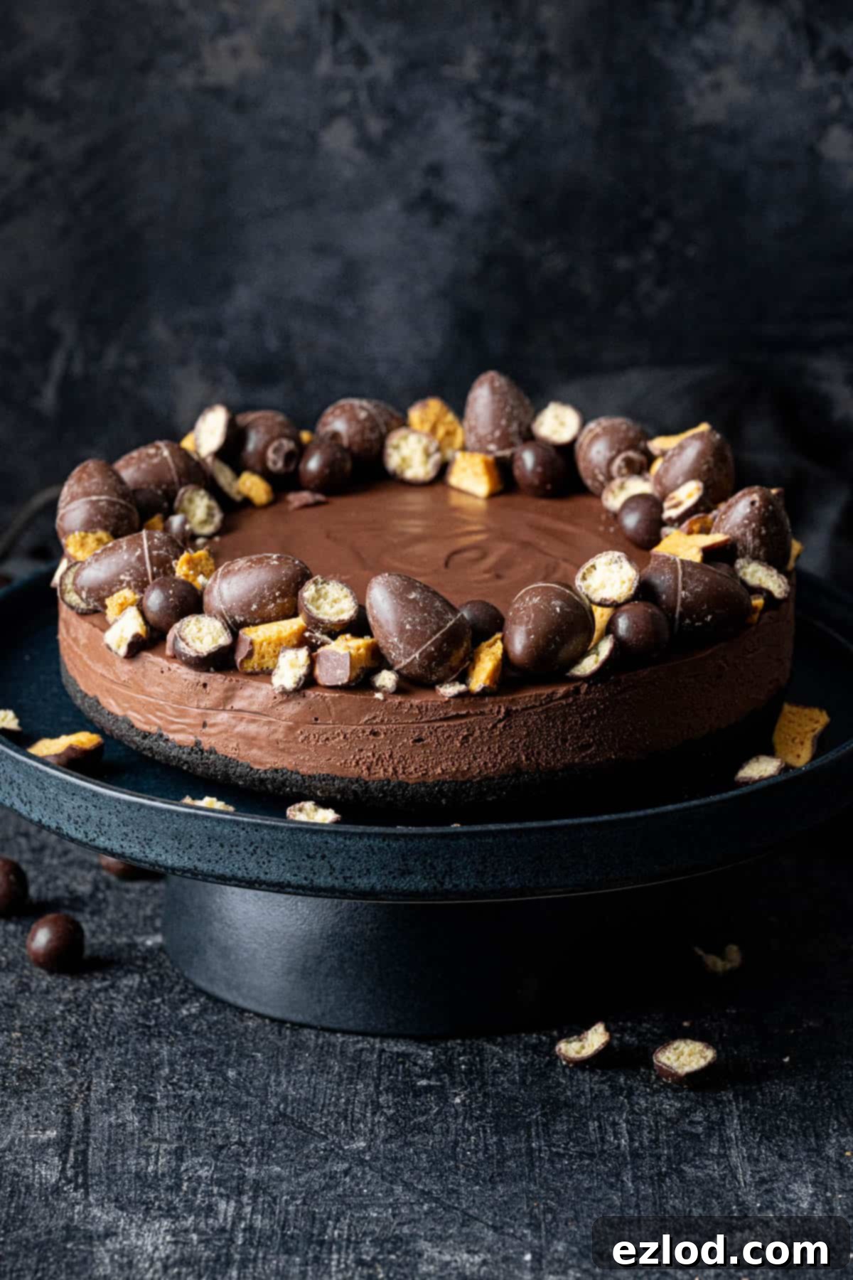 Velvet Vegan Chocolate Cheesecake 11 Decorated vegan chocolate cheesecake on a black cake stand on a black background.