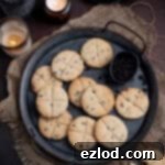 Homestyle Vegan Soul Cakes 13 Vegan soul cakes on a metal tray on a dark surface with candles and cups of coffee.