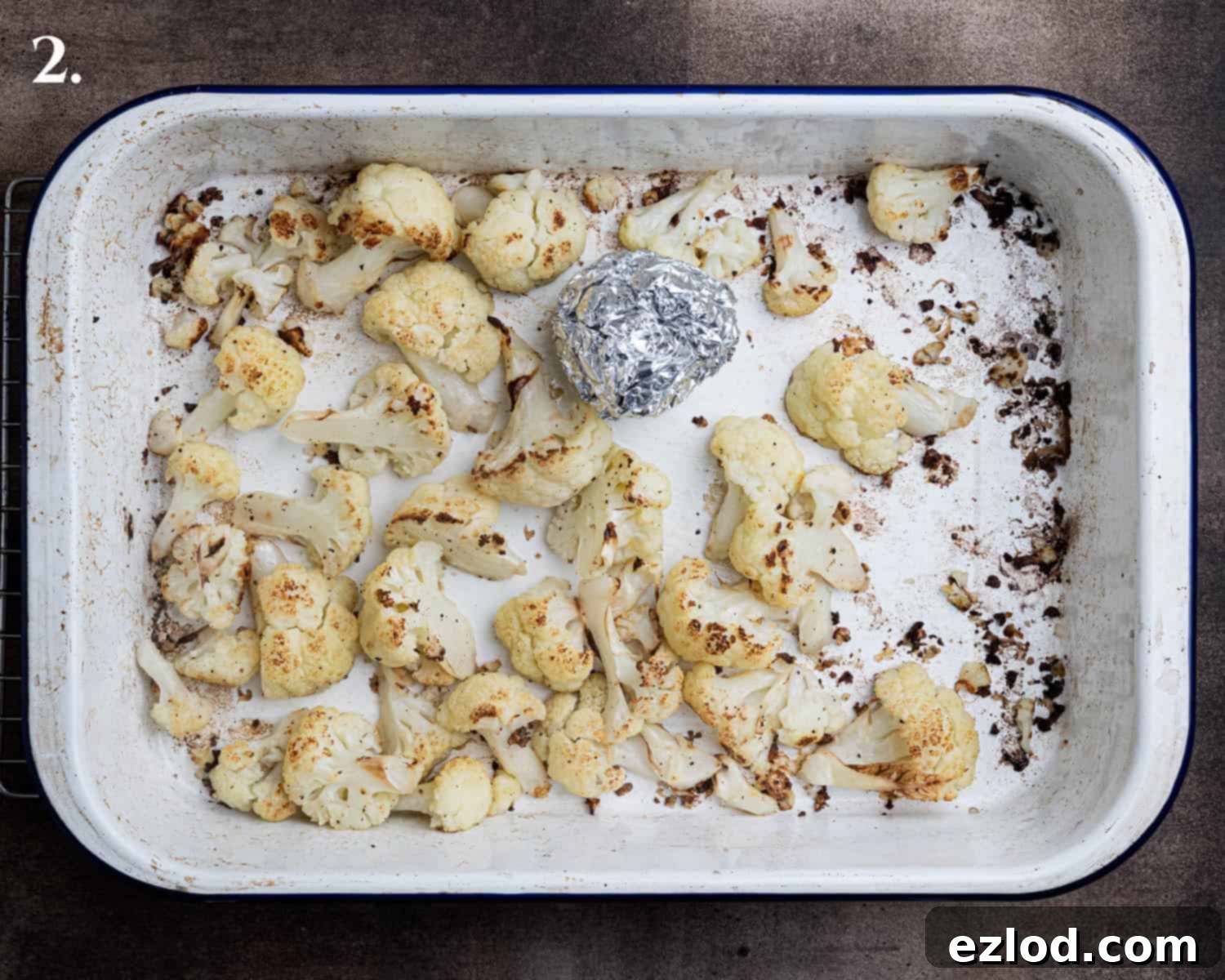 Velvety Vegan Roasted Garlic Cauliflower Soup 6 Step 2: Golden and tender roasted cauliflower florets spread across a roasting tin, showing perfect caramelization.