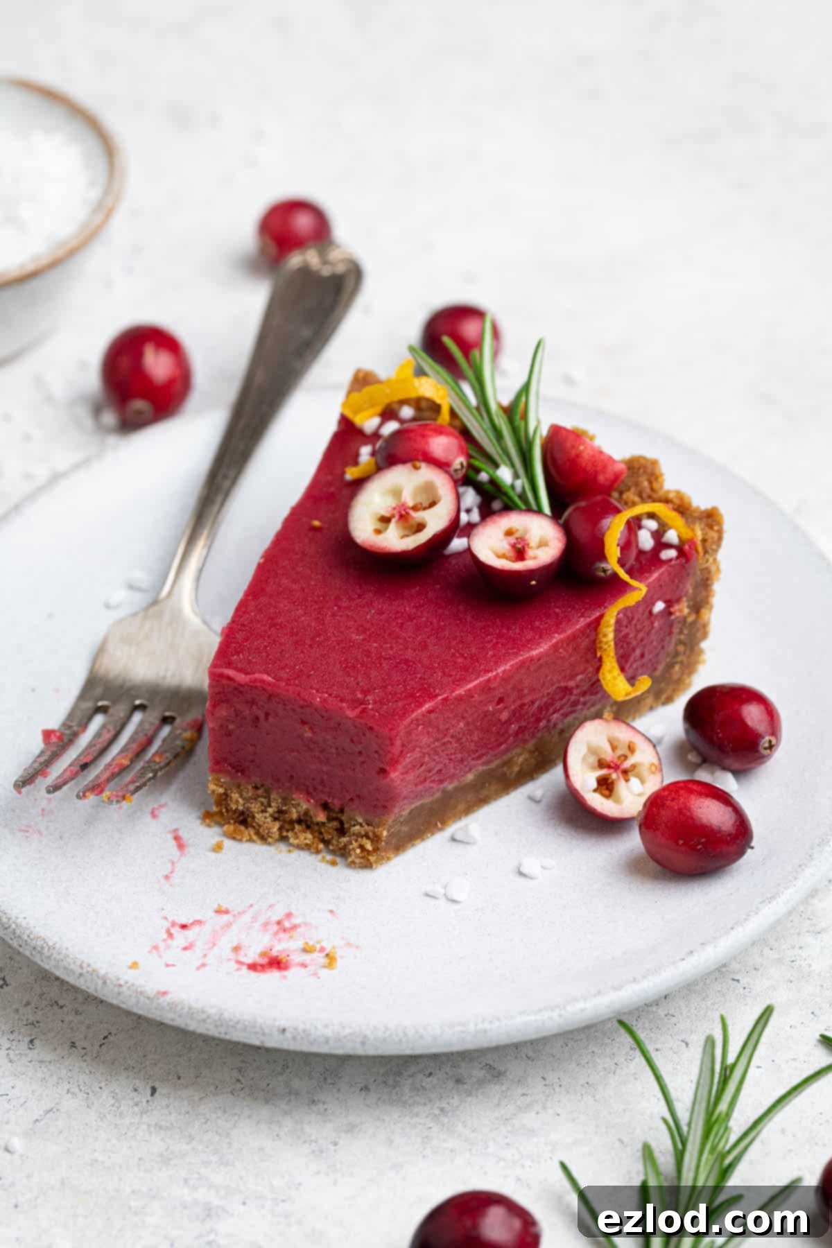 Zesty Vegan Cranberry Curd Tart 15 A partially eaten slice of Vegan Cranberry Curd Tart on a white plate, highlighting its deliciousness and inviting texture.