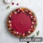 Zesty Vegan Cranberry Curd Tart 16 Vegan cranberry curd tart on a white plate on a white surface with a bowl of pearl sugar.