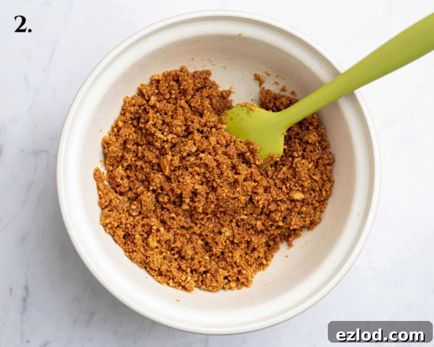 Zesty Vegan Cranberry Curd Tart 7 Step 2: Crushed gingernut biscuits mixed with melted vegan butter, resembling damp sand, in a bowl.