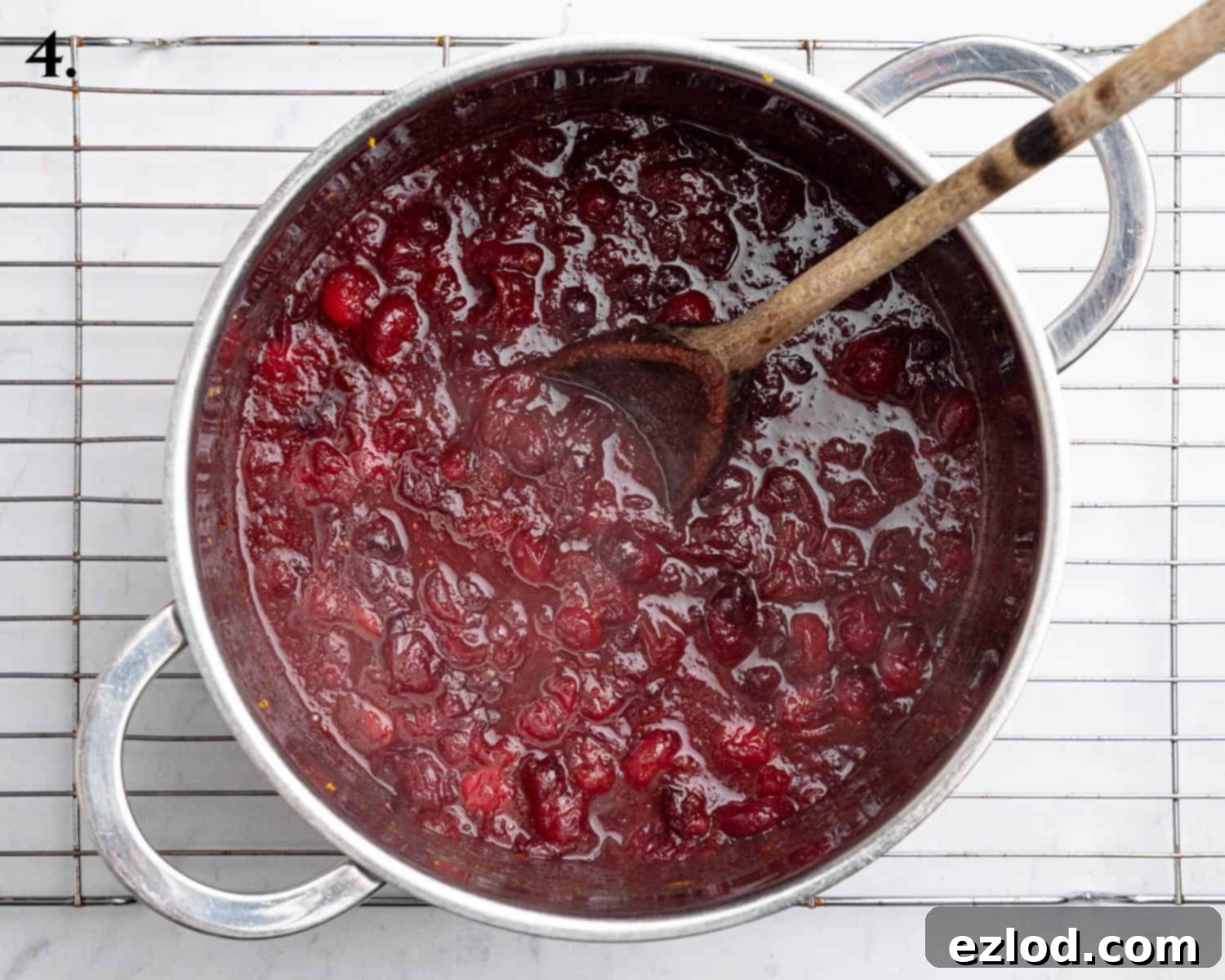 Zesty Vegan Cranberry Curd Tart 9 Step 4: Cooked cranberries simmering with orange juice, zest, sugar, and spices in a saucepan, softened and burst.