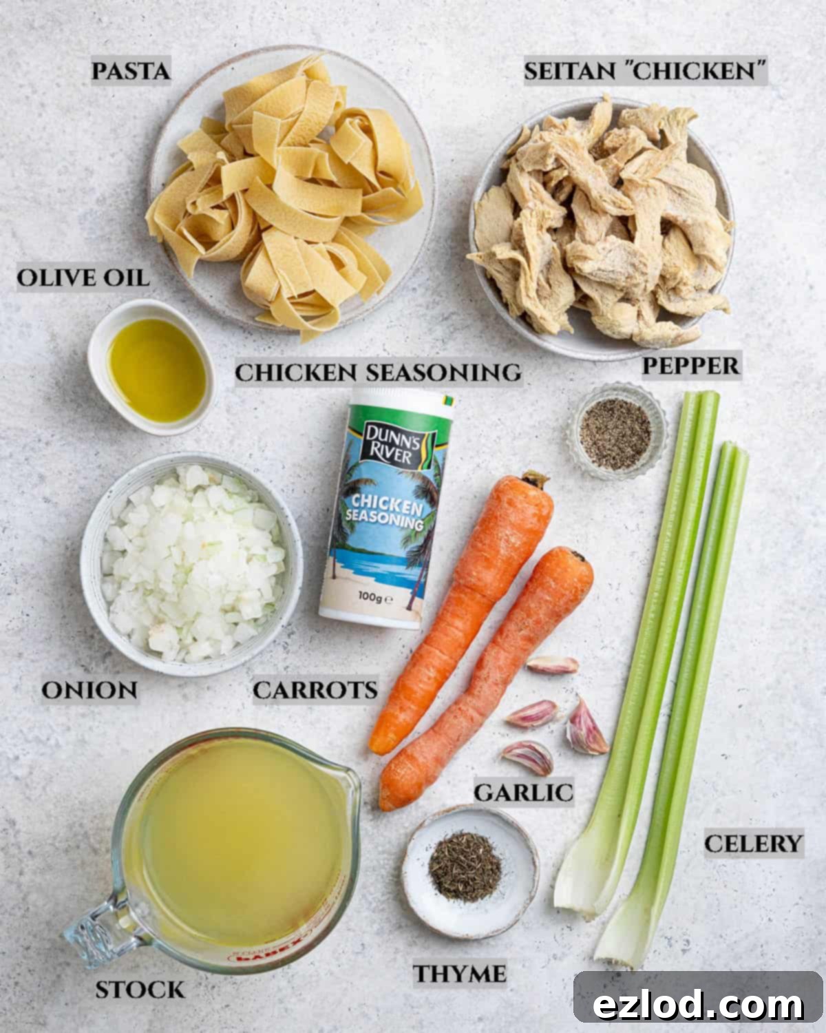 Plant-Based Chicken Noodle Soup 3 A flat lay photo displaying all the fresh and dry ingredients needed to prepare vegan chicken noodle soup, neatly arranged on a white surface.