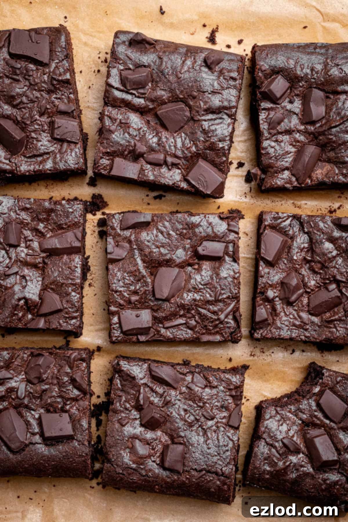 Vegan Chocolate Orange Fudge Brownies 10 Vegan chocolate orange brownies on a sheet of baking paper, one with a bite taken out of it.