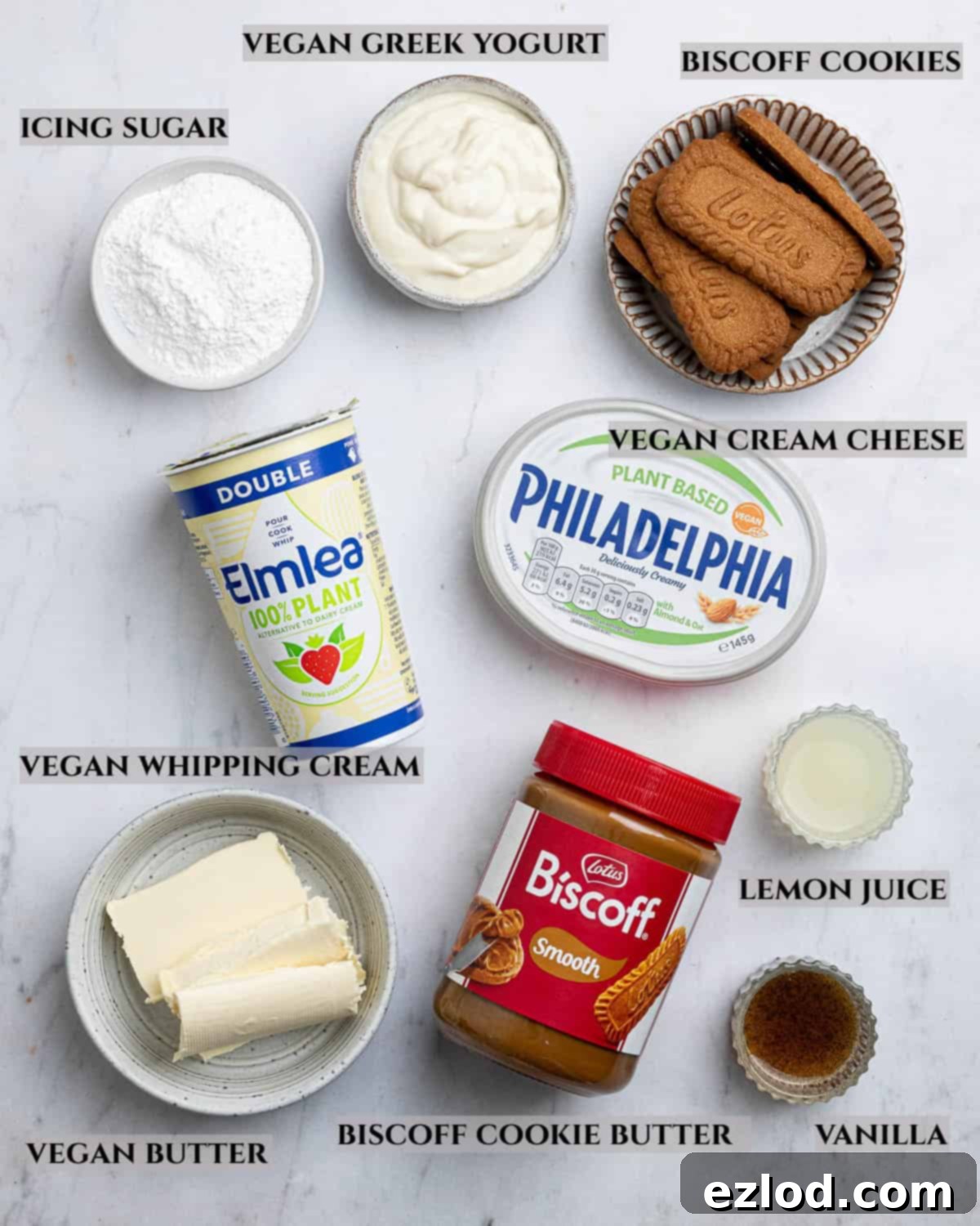 Decadent Vegan Biscoff Cheesecake 3 A clearly labelled photo of the ingredients needed to make vegan Biscoff cheesecake, including Biscoff cookies, spread, vegan cream cheese, whipping cream, yogurt, lemon juice, vanilla, icing sugar, and vegan butter.