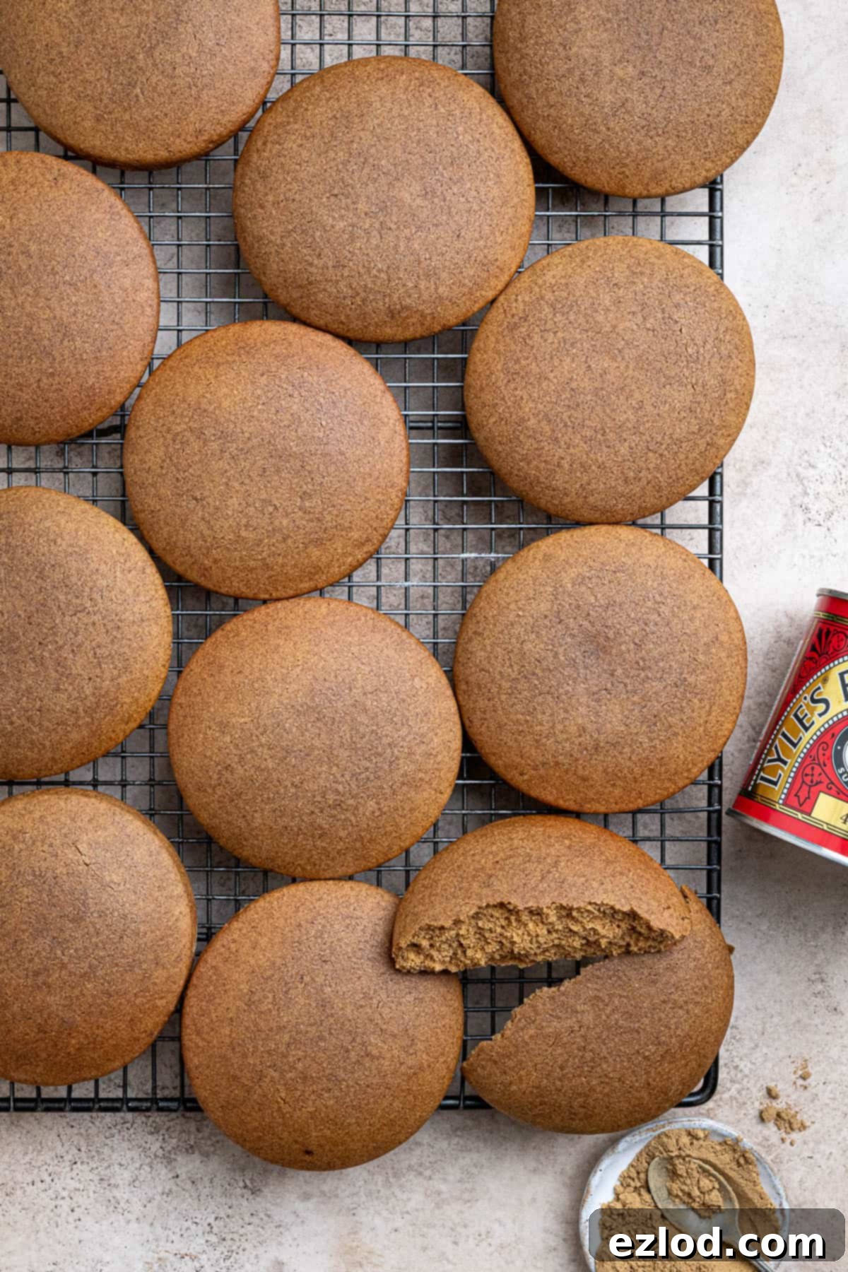 Plant-Based Jamaican Bulla Delight 4 Several freshly baked vegan Jamaican bulla cakes cooling on a metal wire rack, showcasing their round shape and slightly crinkled, golden-brown tops.