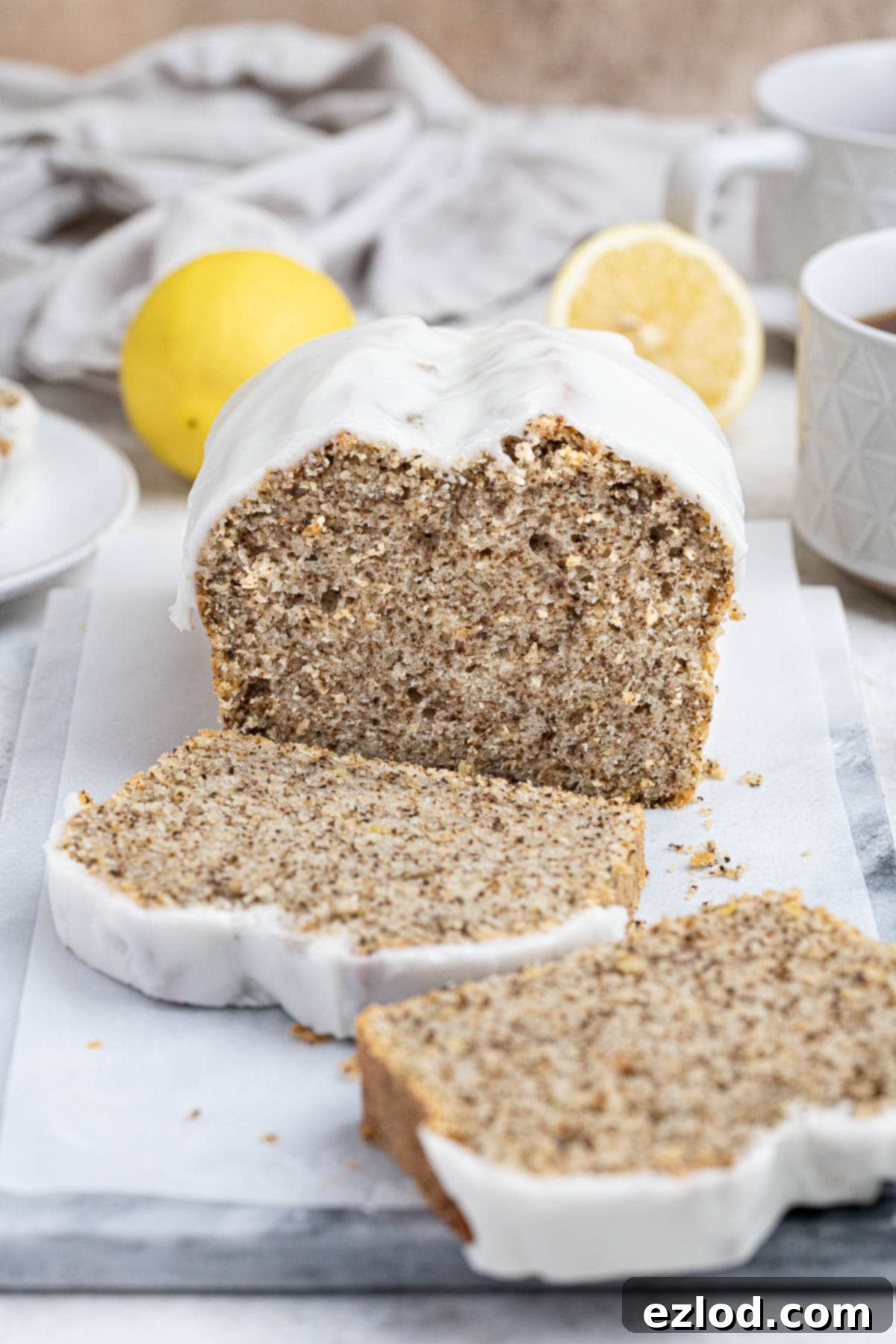 Zesty Vegan Earl Grey Lemon Cake 2 A beautifully sliced vegan Earl Grey lemon cake on a marble board, accompanied by steaming cups of tea and fresh lemon slices, highlighting its soft texture and inviting aroma.