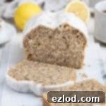 Zesty Vegan Earl Grey Lemon Cake 11 A close-up of a vegan Earl Grey lemon cake, perfectly baked and ready to be served, alongside cups of tea and lemon slices on a marble board.