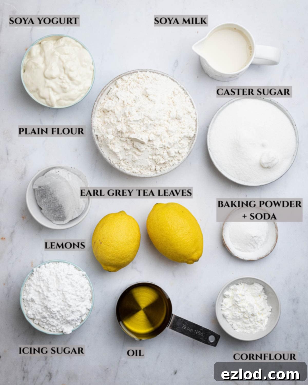 Zesty Vegan Earl Grey Lemon Cake 3 A detailed layout of all the essential ingredients required to bake a homemade vegan Earl Grey lemon loaf cake, including tea, lemons, plant-based yogurt, and flour.
