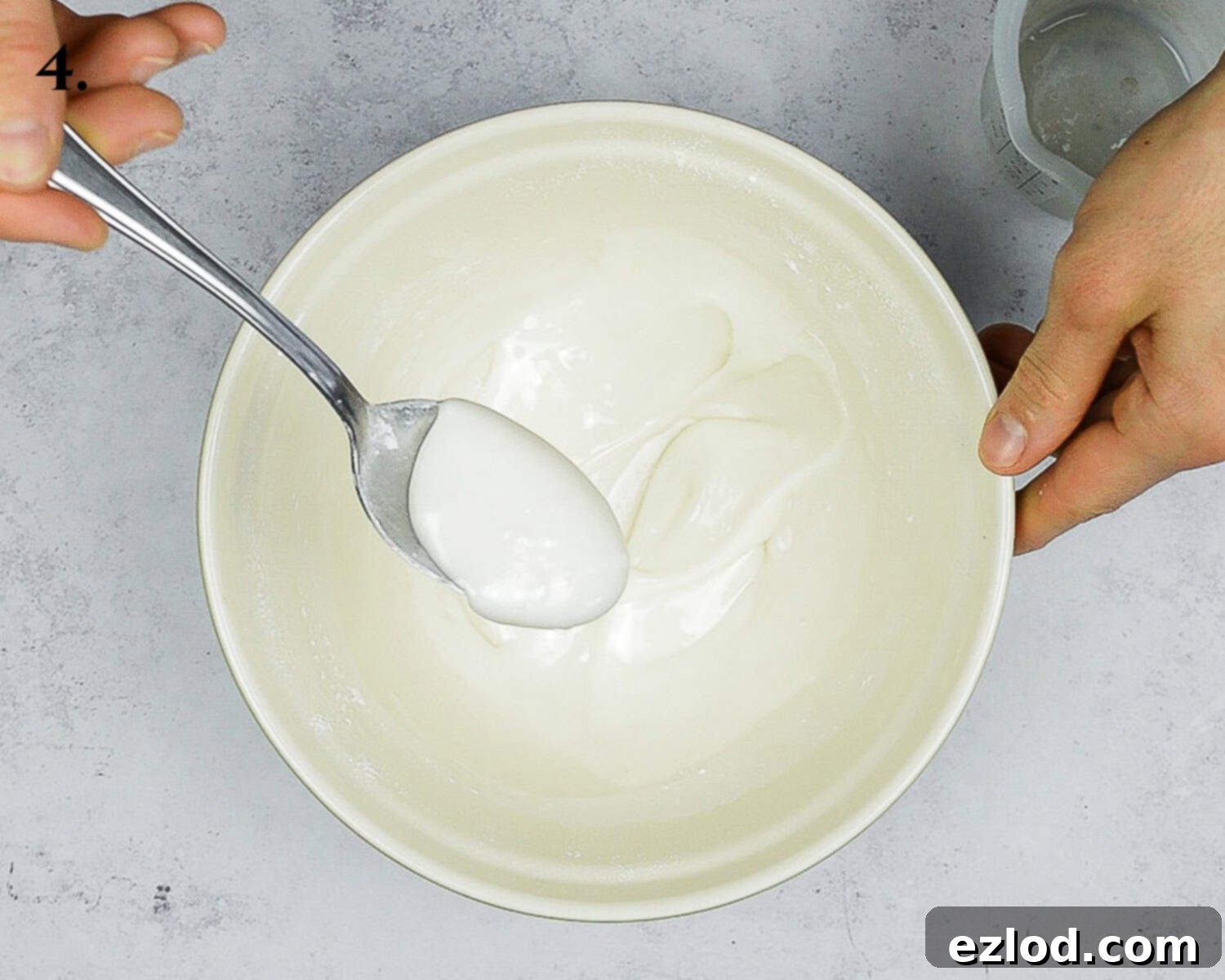 Zesty Vegan Earl Grey Lemon Cake 8 Step 4 in making vegan Earl Grey lemon cake: a vibrant lemon glaze, made from sifted icing sugar, lemon juice, and vegan yogurt, is prepared in a bowl, ready to be poured over the cooled cake.