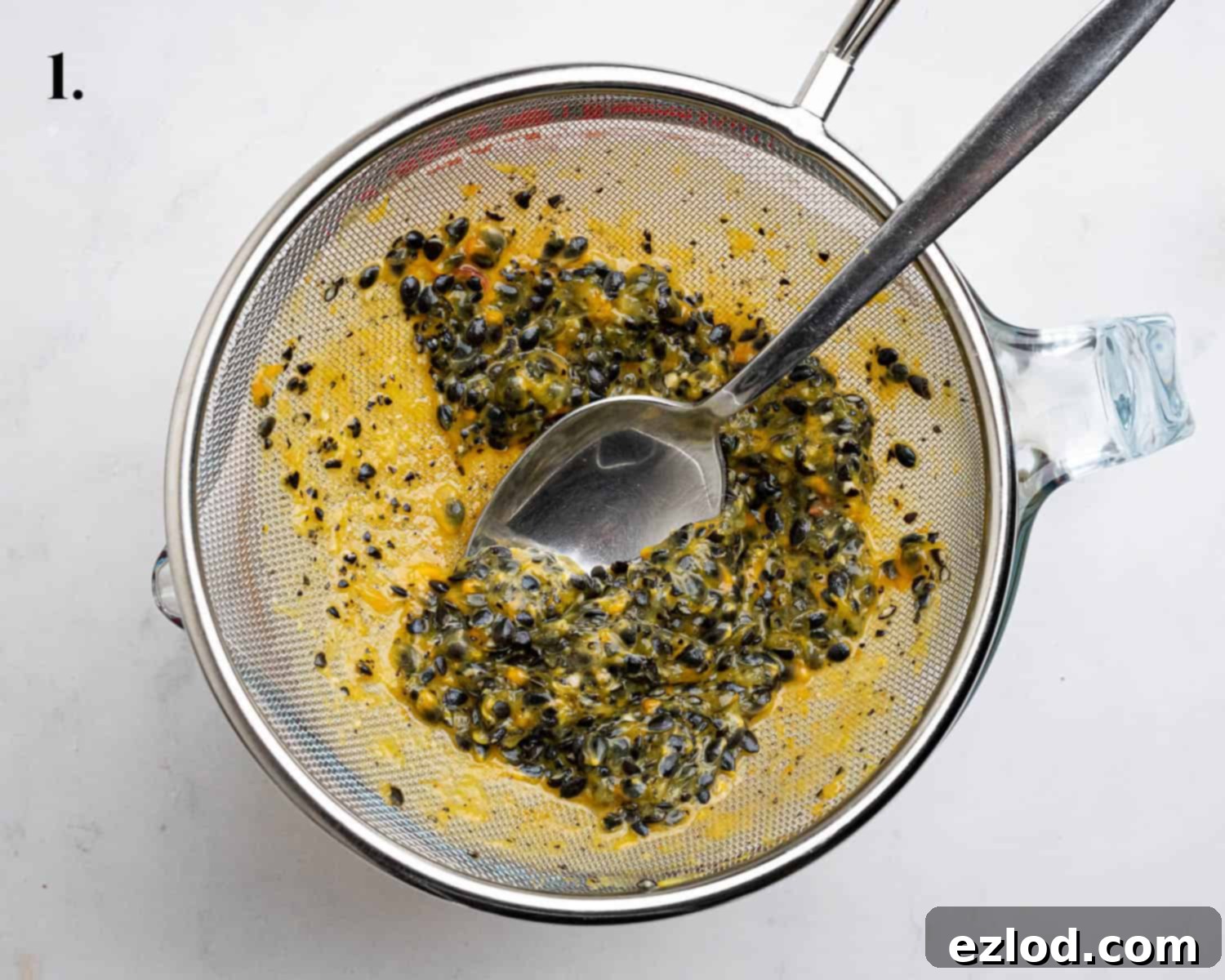 Luscious Vegan Passion Fruit Delight 5 Step 1 in making vegan passion fruit cake: Straining the vibrant passion fruit pulp through a fine mesh sieve to separate juice from seeds.