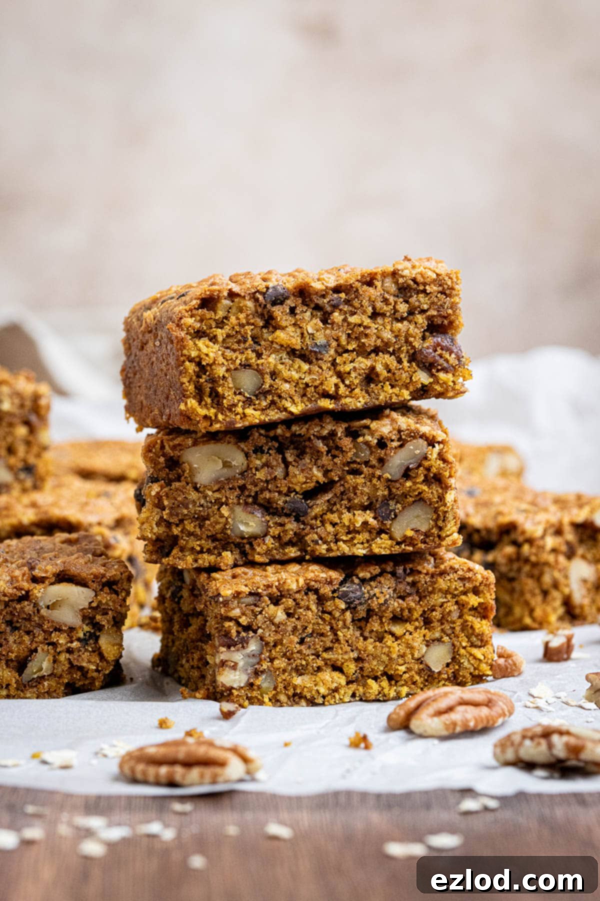Vegan Pumpkin Spice Oat Bars 2 A stack of vegan pumpkin oatmeal cookie bars on a sheet of baking paper.
