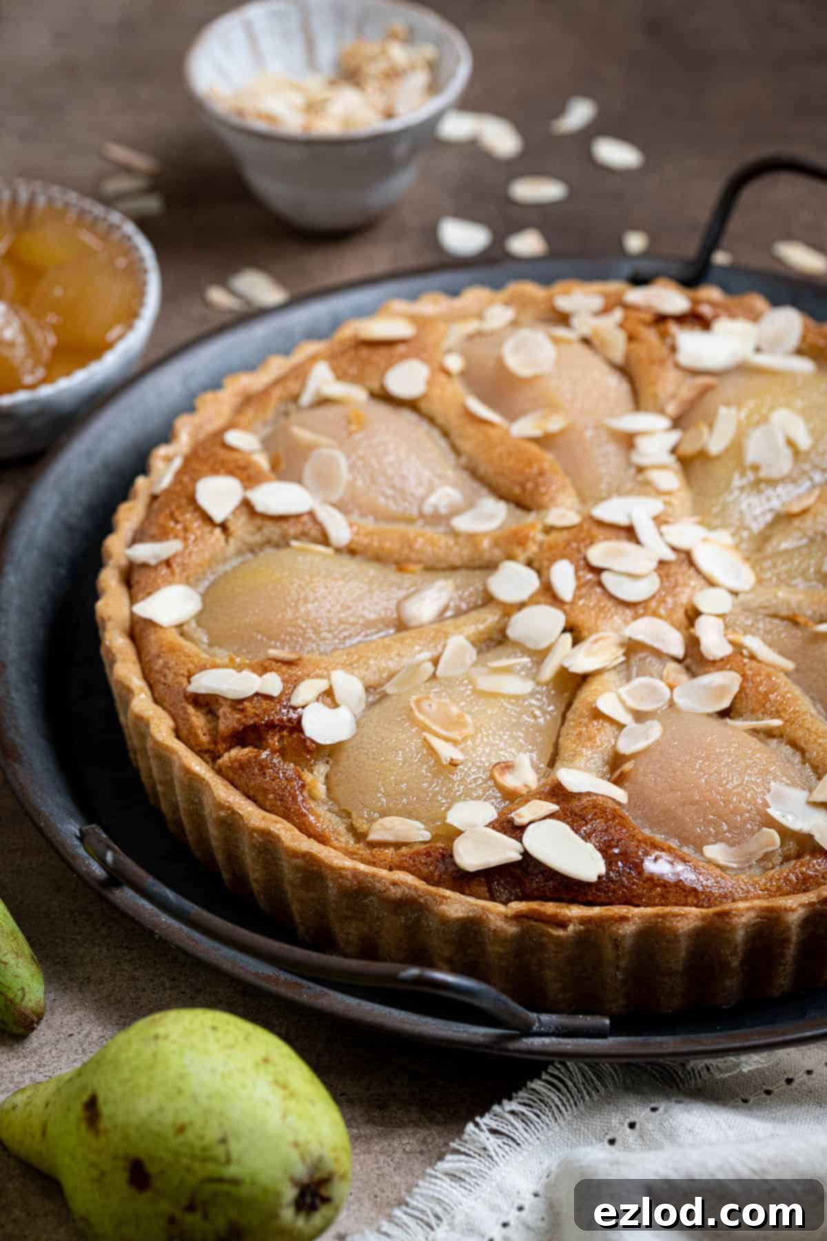 Gingered Pear & Almond Vegan Tart 16 A close-up shot of the exquisite vegan pear, ginger, and almond tart resting on a metal tray, highlighting its golden crust and delicious filling.