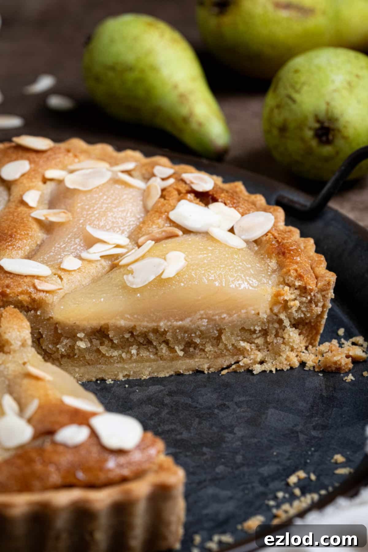 Gingered Pear & Almond Vegan Tart 4 A mouth-watering close-up of a slice of vegan pear, ginger, and almond tart, revealing its layers of pastry, frangipane, and tender pears.