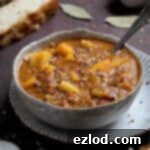 Mediterranean Sunshine Lentil Soup (Vegan) 6 A bowl of vegan sun dried tomato lentil soup on a plate with slices of bread.