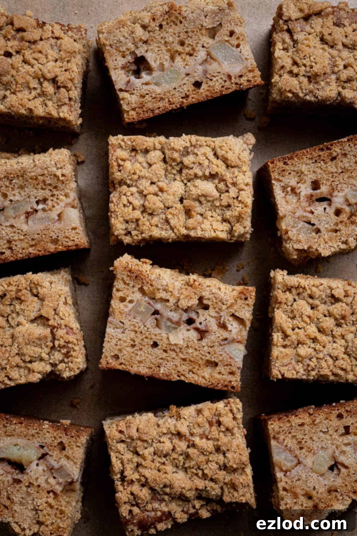 Spiced Vegan Apple Streusel Cake 4 Squares of perfectly baked vegan apple crumb cake arranged artfully on a sheet of baking paper, highlighting the golden streusel topping.