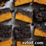 Squares of vegan pumpkin chocolate crumb cake on a sheet of baking paper.