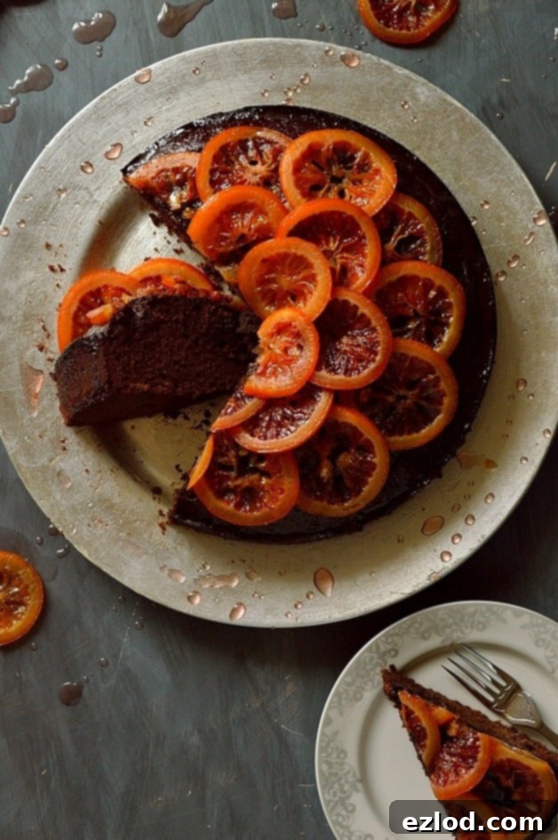 Aromatic Chocolate Olive Oil Rosemary Cake with Candied Blood Oranges 1 Beautifully sliced chocolate olive oil and rosemary cake adorned with vibrant candied blood orange slices on a white platter, showcasing its moist texture and rich flavors.