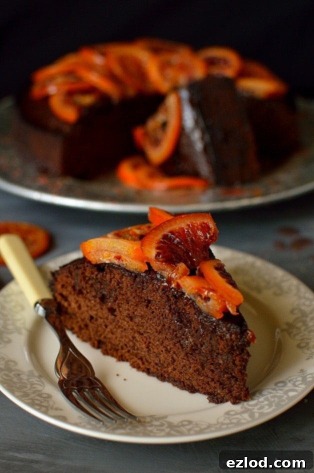 Aromatic Chocolate Olive Oil Rosemary Cake with Candied Blood Oranges 2 Close-up of a slice of chocolate, olive oil, and rosemary cake, revealing its delicate crumb and the glistening candied blood orange on top, promising a fragrant and delicious bite.