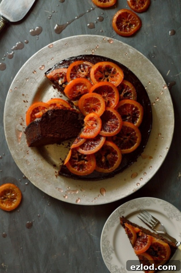 Aromatic Chocolate Olive Oil Rosemary Cake with Candied Blood Oranges 4 A whole chocolate cake infused with olive oil and rosemary, garnished with glistening candied blood orange slices and aromatic orange syrup, offering a tantalizing view of its deliciousness.
