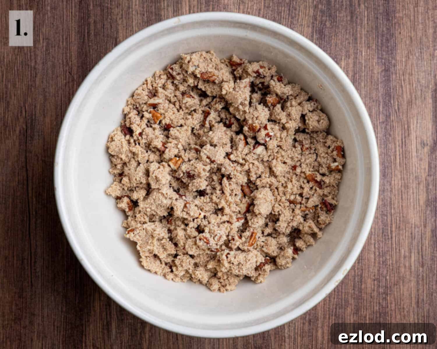 Spiced Vegan Pumpkin Streusel 5 Step 1: The streusel topping ingredients are mixed in a bowl, resembling breadcrumbs with chopped pecans visible, ready for chilling.