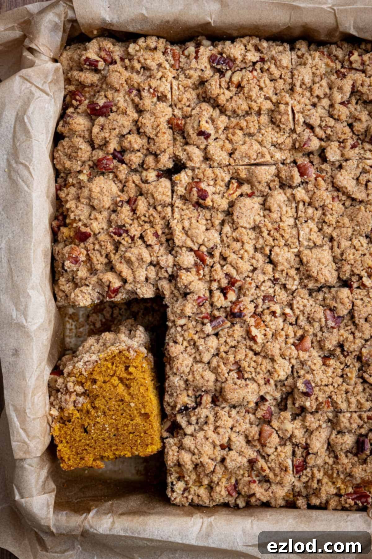 Spiced Vegan Pumpkin Streusel 10 A beautifully baked vegan pumpkin crumb cake in its square tin, with one slice already removed, showcasing its moist interior and golden-brown, crunchy streusel.