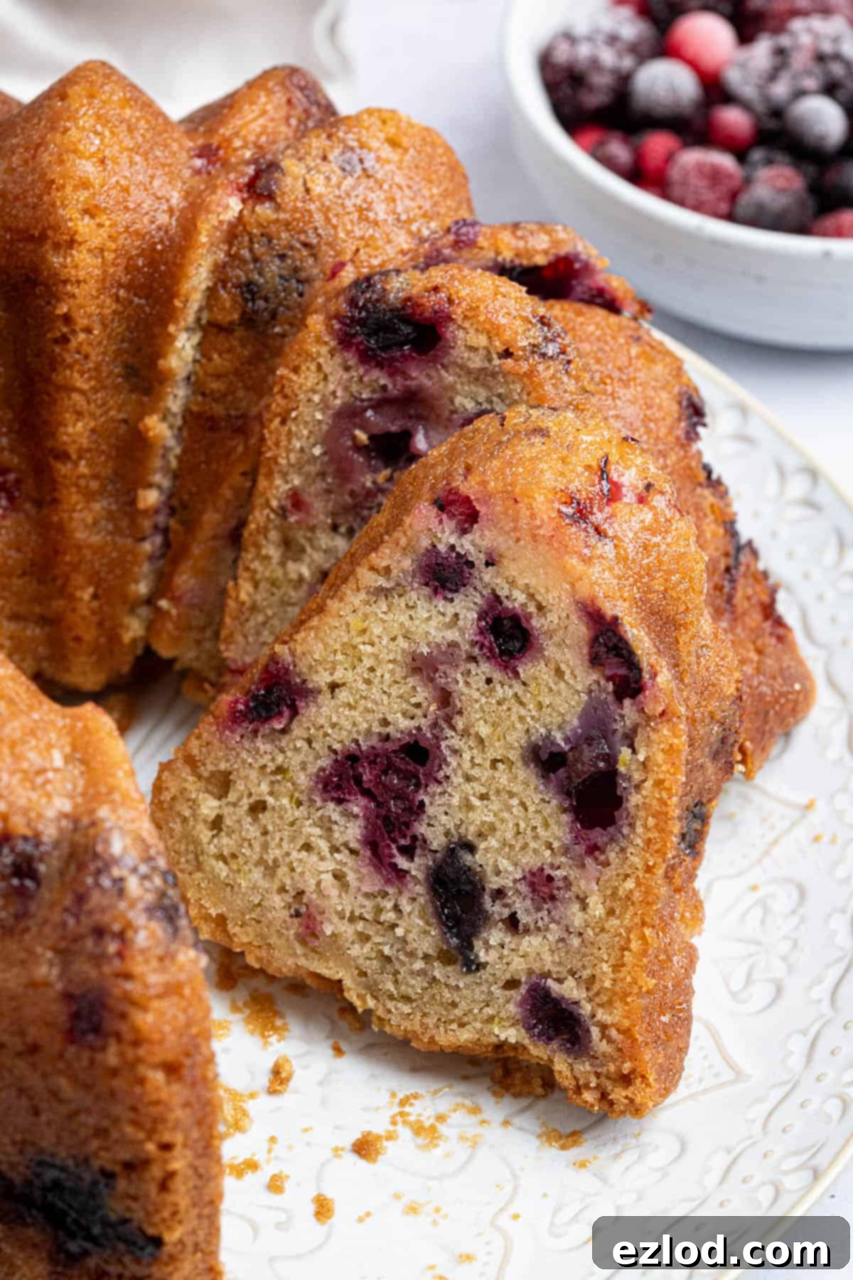 Vegan Berry Lime Bundt Cake 12 A stunning close-up of a single slice of vegan berry lime bundt cake, showcasing its moist texture, visible berry pieces, and the delicate sheen of the lime drizzle.