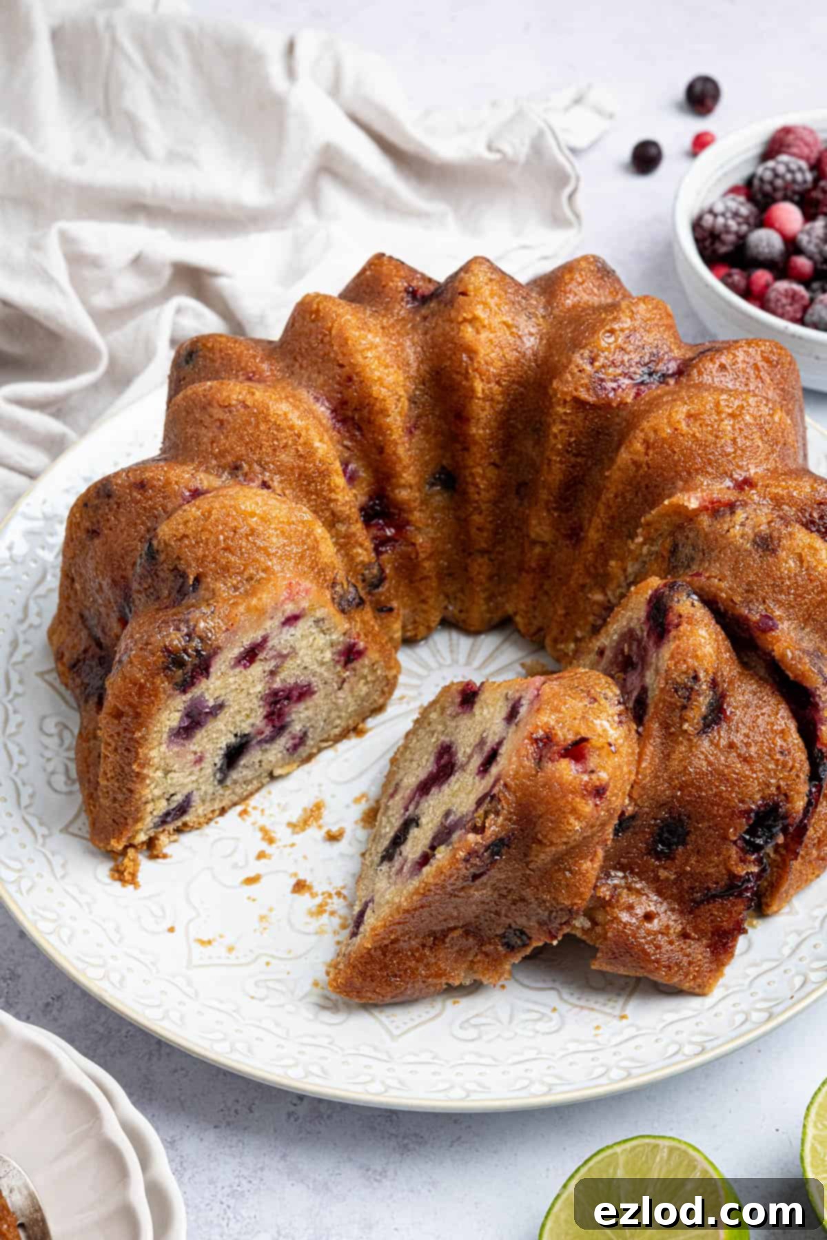 Vegan Berry Lime Bundt Cake 13 The stunning sliced vegan berry lime bundt cake, elegantly presented on a white plate, inviting a taste of its moist, fruity goodness.