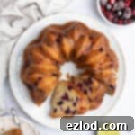 Vegan Berry Lime Bundt Cake 14 Vegan berry lime bundt cake on a white plate with a bowl of frozen berries.