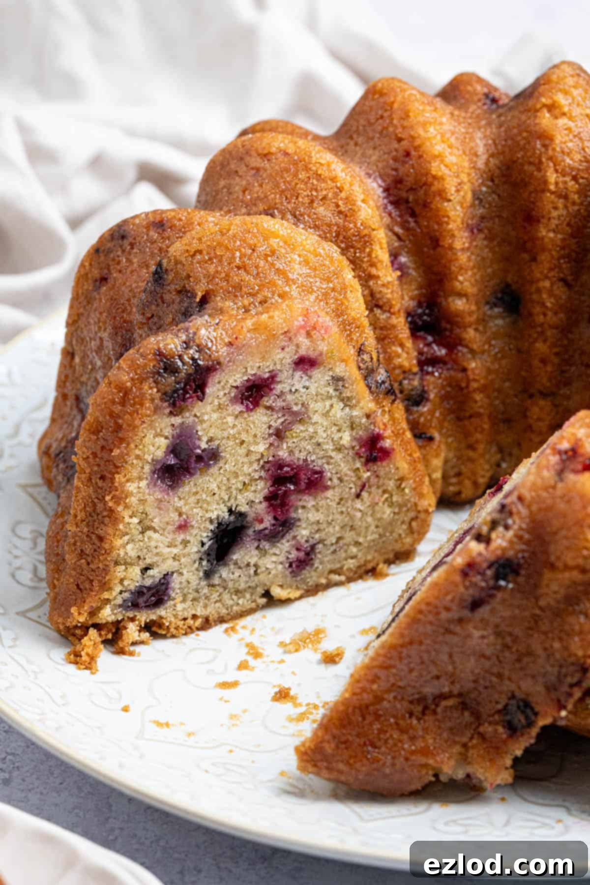 Vegan Berry Lime Bundt Cake 4 A tantalizing close-up shot of a perfectly sliced vegan berry lime bundt cake, revealing its moist interior, vibrant berries, and glossy lime drizzle.