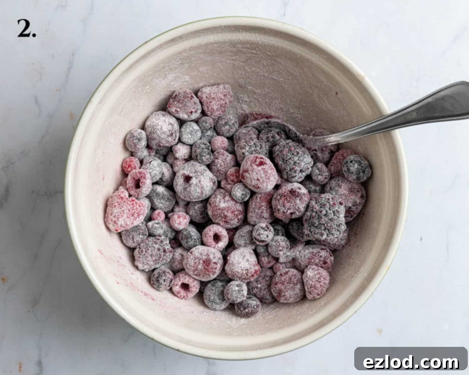 Vegan Berry Lime Bundt Cake 6 Step 2 in making berry lime bundt cake: a bowl of mixed berries perfectly coated in a light dusting of flour, ready to be folded into the cake batter.