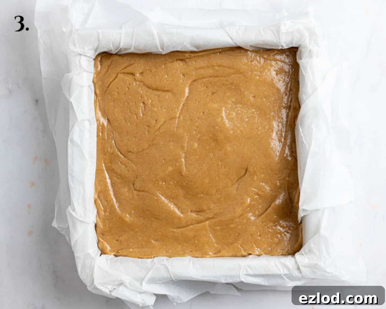 Irresistible Vegan Peanut Butter Blondies 7 Step 3: The rich blondie batter is scraped into a parchment-lined 20cm square baking tin and spread evenly.