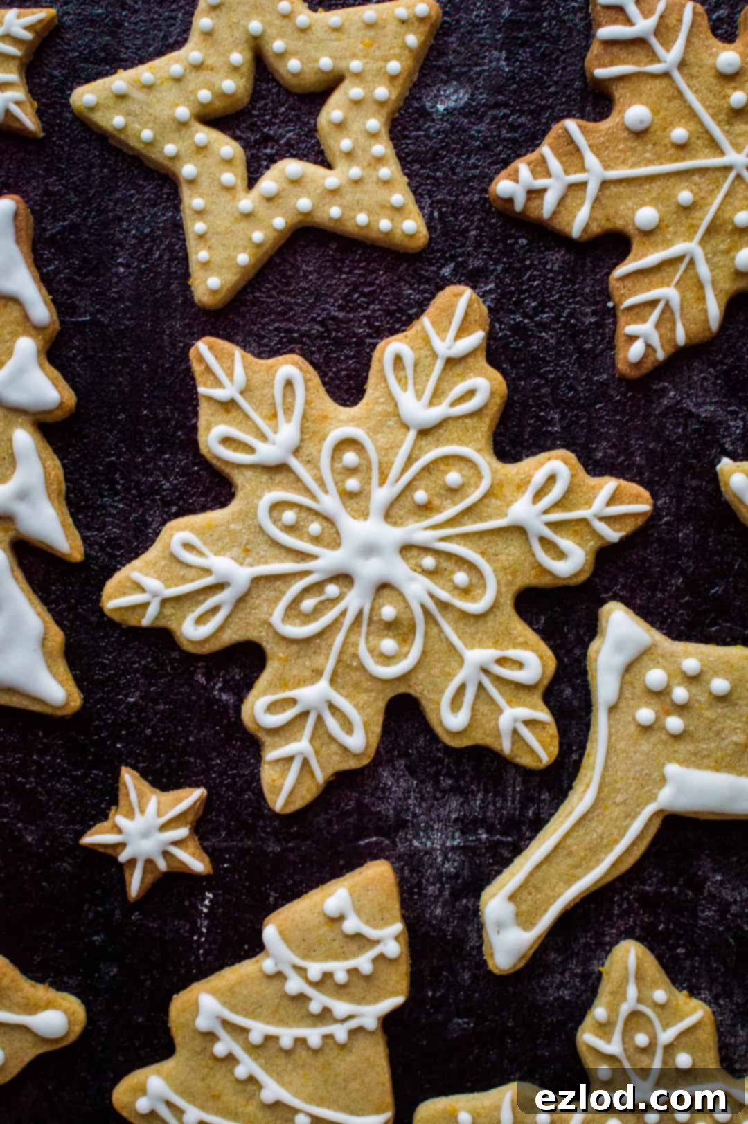 A single, perfectly decorated orange cinnamon butter biscuit shaped like a snowflake, adorned with an elegant white royal icing design, resting on a flat surface, ready to be enjoyed.
