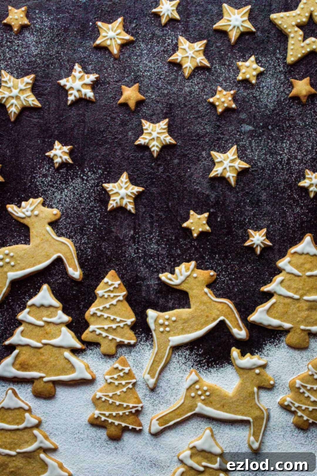 A festive array of orange cinnamon butter biscuits with white royal icing, arranged like a winter wonderland scene, showcasing various holiday shapes and intricate details.