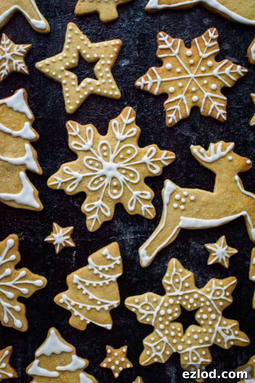 Buttery Orange Cinnamon Biscuits 8 An enchanting display of beautifully decorated orange and cinnamon butter cookies. The biscuits, shaped as reindeer, Christmas trees, snowflakes, and stars, feature elegant white royal icing designs, creating a stunning visual for holiday celebrations.