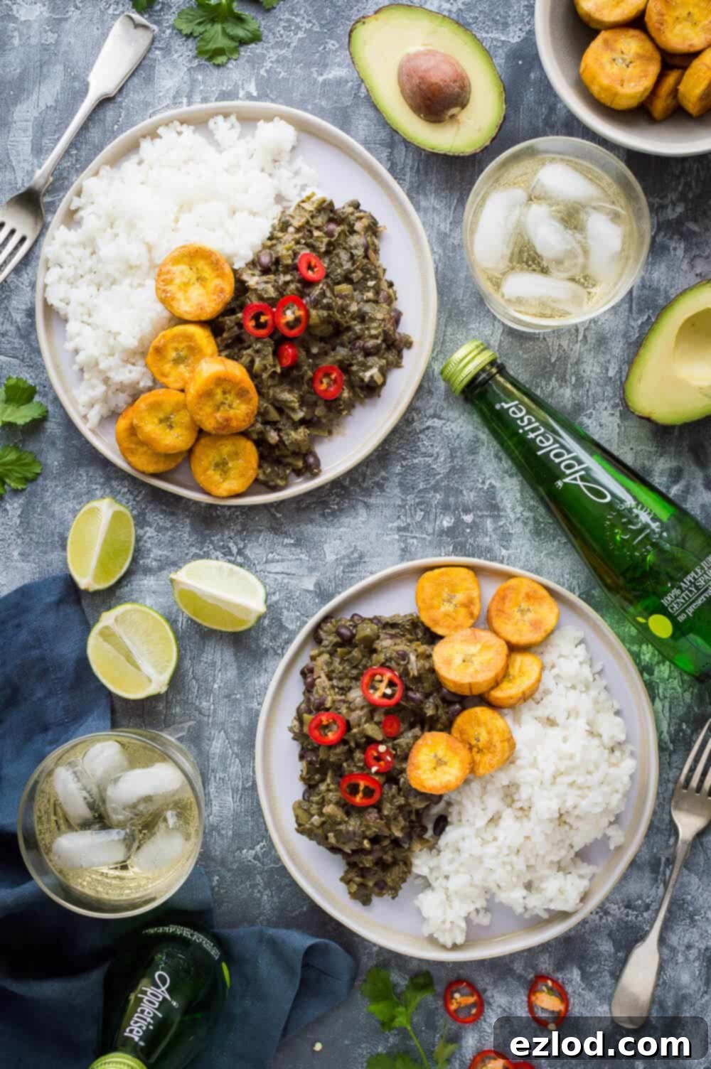 Aromatic Caribbean Medley with Coconut Rice and Sweet Plantain 4 Two plates of vegan beans and greens, coconut rice and fried plantain with lime slices, avocado and Appletiser.